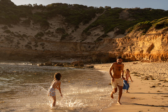 A family playing together at the beach, at golden time.