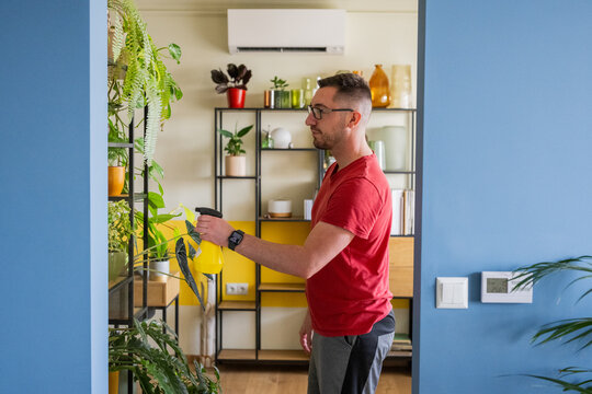 Young adult misting home plants