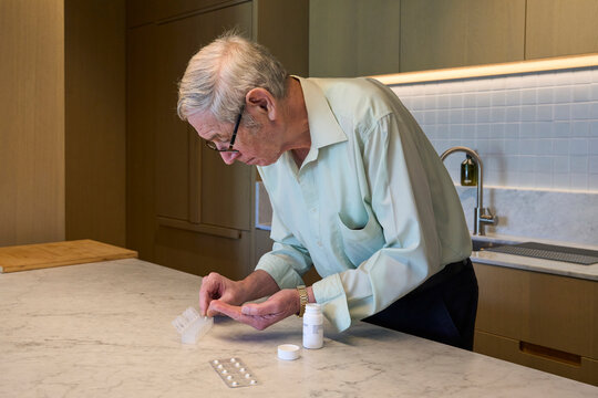 An senior man sorts pills into a weekly organizer