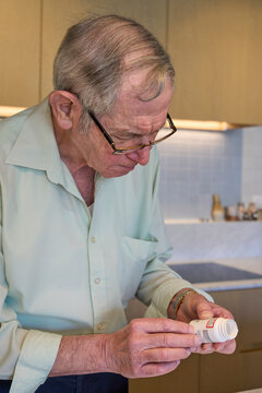 Senior man reviewing medicine bottle in modern kitchen space