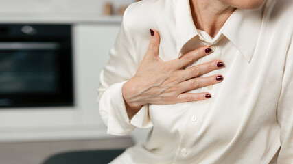 A mature woman feels chest pain while seated in her living room