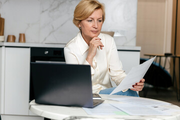 Working on finances with bills and a laptop in a home setting during the day