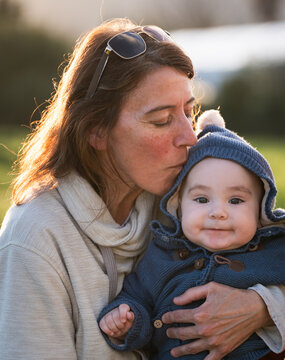Loving mother kissing her adorable baby boy on the forehead