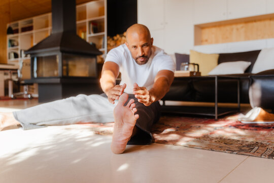 Fit Man Stretching in Yoga Pose, Reaching Toward Toe on Sunny Morning
