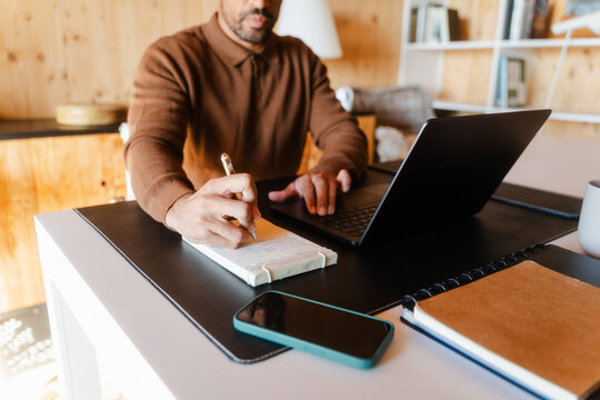 Businessman Taking Notes while Working in Log Cabin Home Office