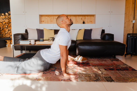 Man Doing Cobra Pose Yoga, Stretching Back Indoors on a Sunny Morning