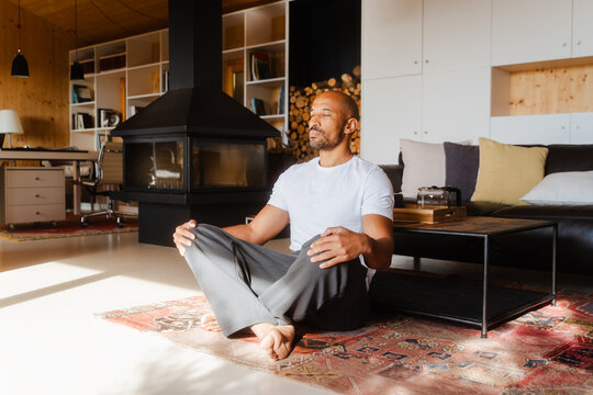 Man Meditating Cross-Legged with Eyes Closed in Tranquil Log Cabin