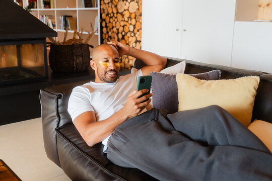 Relaxing with Collagen Gel Patches, Bald Male Texting on Phone at Home