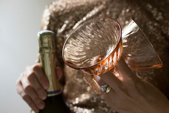 Woman in sparkled top holds pink champage glasses