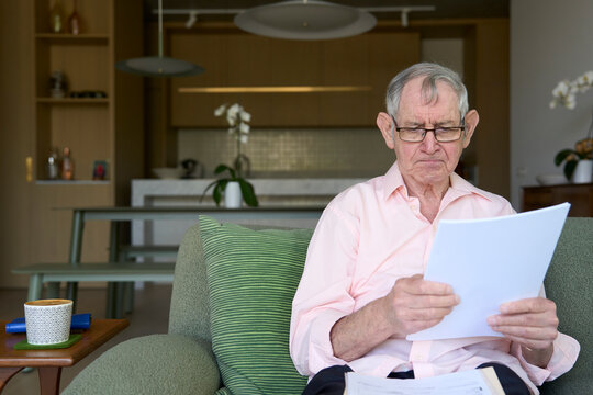 Elderly man reading documents in a modern living room space