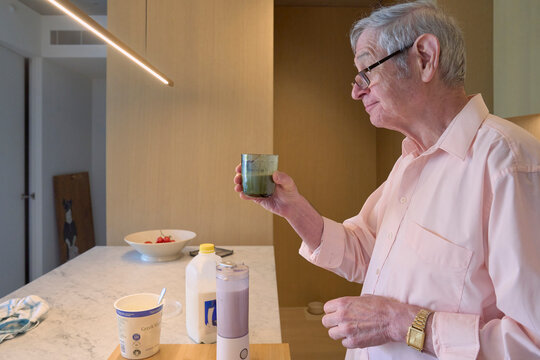 Senior man enjoying a smoothie in a modern kitchen setting
