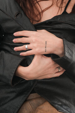 Close-up of hands showcasing minimalistic tattoos and stylish rings 