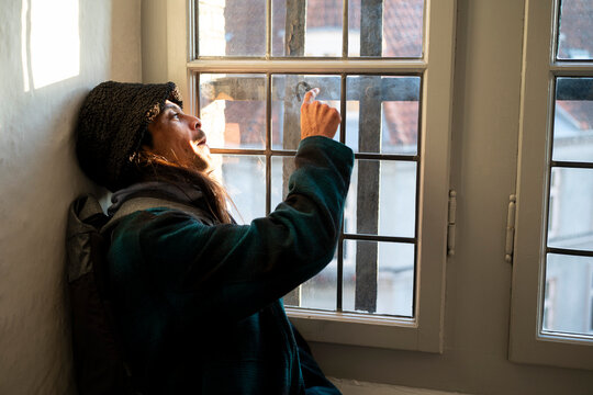Young man drawing heart on window 