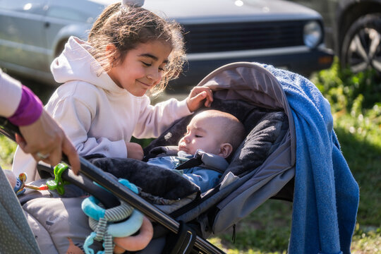 Sister caring for baby brother in stroller