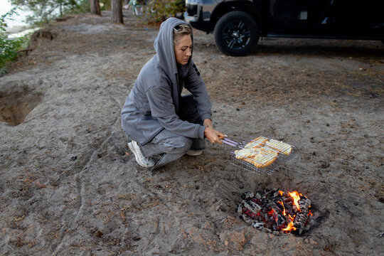 a woman  toasts bread for hotdogs