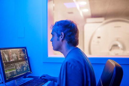 Medical specialist analyzing data on computer near MRI machine