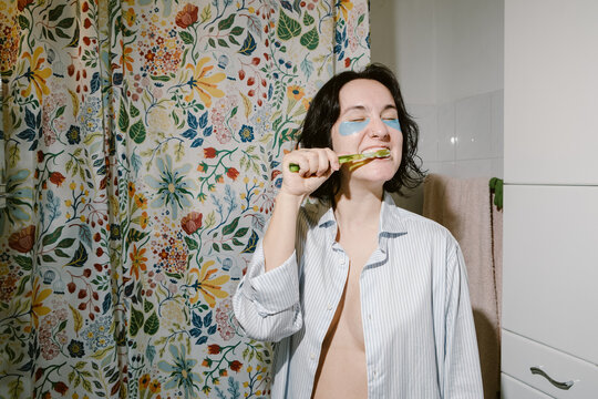 Woman with Eye Patches is Brushing her Teeth