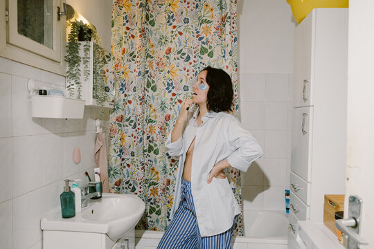 Woman with Eye Patches is Brushing her Teeth