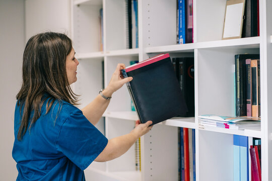 Veterinarian searching for information in a book on a library shelf