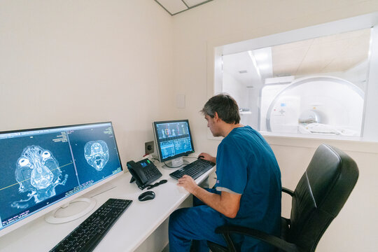 Veterinarian analyzing cat scan using computer next to ct scanner