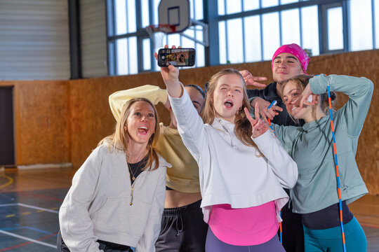Teenager group united by frinedship taking selfie in school gymnasium