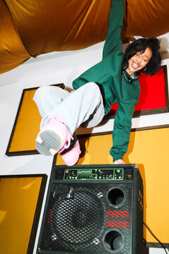 Playful woman jumping above a speaker