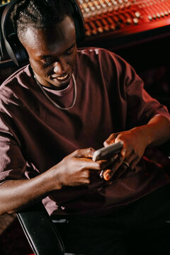 Man Smiling While Using Smartphone in Studio