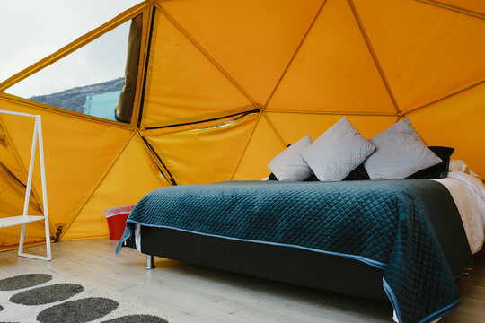 Comfortable bed inside geodesic dome tent glamping accommodation
