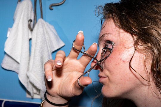 Teen apply makeup on eyelash curler