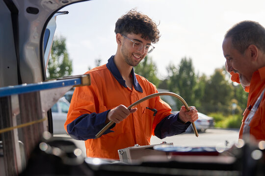 Aprrentice collaborating on plumbing equipment in a service van