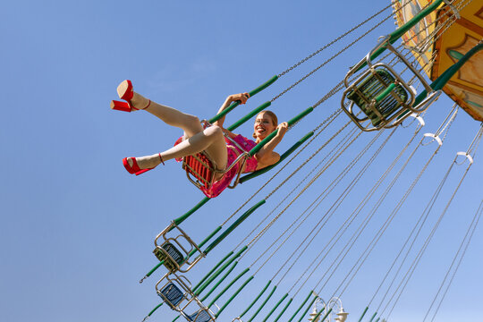 A stylish girl rides on a swing in an amusement park.