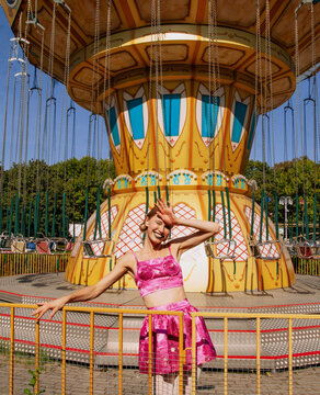 Happy girl standing in front of a carousel swing ride.