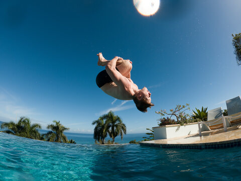 Swimming pool with teenage doing flip jumping 