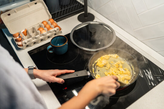 Woman cooking scrambled eggs in modern kitchen in Spain