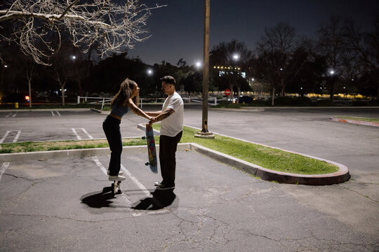 Couple Enjoying Skateboarding Together at Night in an Empty Lot