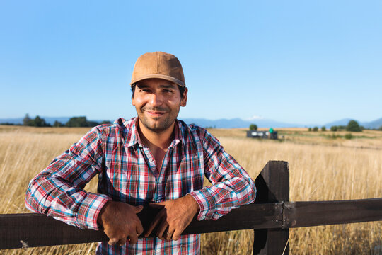 Latin farmer leaning on wooden fence in a dry field