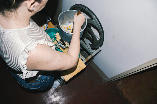 Woman stirring corn in grinding machine