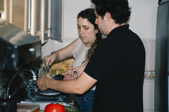 Couple helping each other strain pasta
