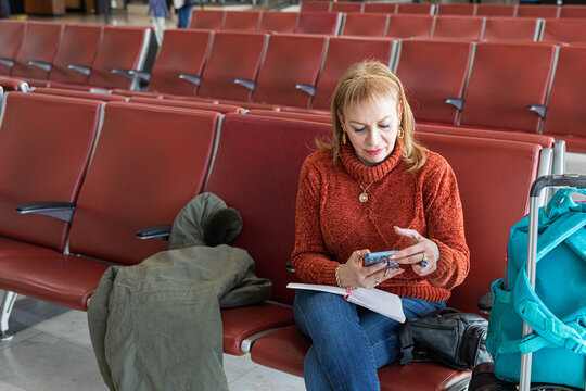 Woman waiting at the airport with her smartphone in hand