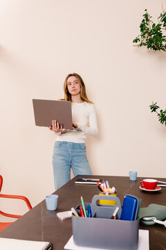 Employee standing with a laptop showing a pensive countenance