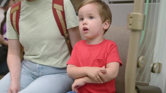 A sweet toddler is riding the subway with his mother. The little baby curiously looks around the subway car and the people around him. The curious boy explores big city life with his parents.