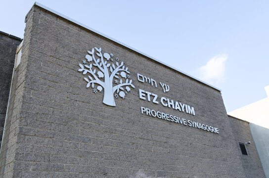 Signage on the exterior wall of Etz Chayim Progressive Synagogue, featuring tree emblem, during a sunny day