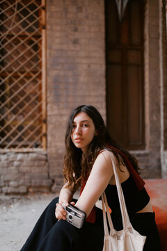 Portrait of young brunette woman with small point and shoot camera