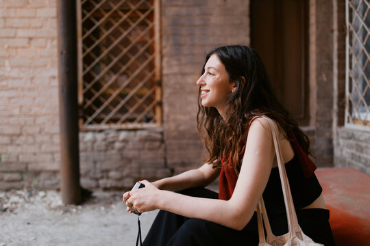 Portrait of young brunette woman with small point and shoot camera