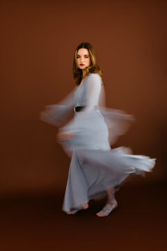 Young woman dancing wearing elegant dress with motion blur effect