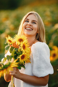 Blonde in a white blouse in a sunflowers field