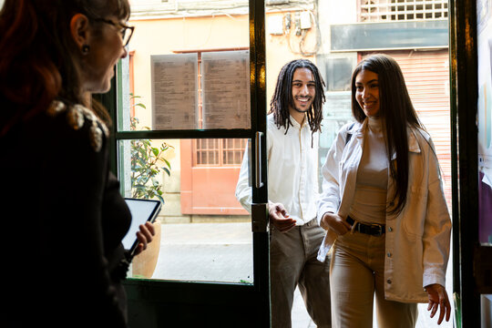 Host welcoming young couple into restaurant 