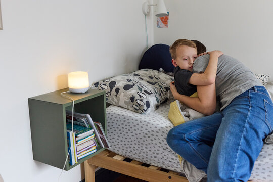 Little boys hugging mom in bed