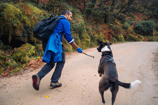 Man playing fetch with a dog on a hiking trail