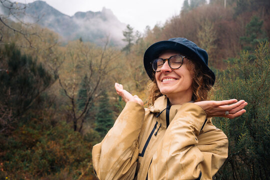 Smiling woman embracing the rain in a misty mountain landscape